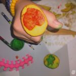 Dziecko trzyma w dłoni model z plasteliny przypominający serce wypełnione pomarańczową masą.