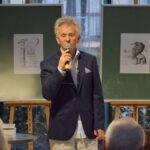 Mirosław Janik przemawia do publiczności, trzymając mikrofon w ręce.