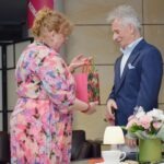 Kobieta wręcza mężczyźnie pakiet zawinięty w kolorowy papier.