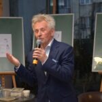 Mirosław Janik przemawia do publiczności, trzymając mikrofon w dłoni podczas spotkania Akademii Słowa.
