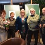 Pięć osób pozuje do zdjęcia przed dwoma obrazami podczas spotkania Akademii Słowa.