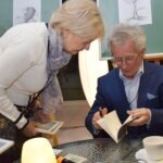 Mężczyzna w garniturze pokazuje kobietę książkę, podczas gdy oboje spoglądają na jej treść.