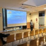 Kobieta stoi przed ekranem, na którym wyświetlana jest prezentacja o interpretacji Biblii.