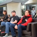 Uczestnicy ChrzanCon siedzą na sofach podczas panelu dyskusyjnego w bibliotece.