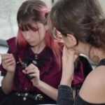 Dwie osoby oglądają przez lornetkę podczas wydarzenia poświęconego popkulturowym inspiracjom.