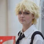 Uczestnik konkursu cosplay prezentuje postać z anime w białej koszuli i czarnym krawacie.