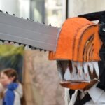 Uczestnik konkursu cosplay prezentuje maskę przedstawiającą potwora z ostrymi zębami.