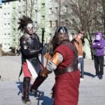 Dwóch mężczyzn przebranych za rycerzy demonstruje umiejętności walki na miejskim placu podczas ChrzanCon.