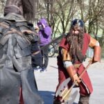 Uczestnik festiwalu ChrzanCon w przebraniu krasnoluda prezentuje miecz bojowy podczas pokazu walki rycerskiej.