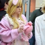 Uczestniczka konkursu cosplay prezentuje postać w różowej stylizacji z charakterystyczną opaską na głowie.