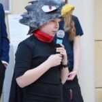 Uczestnik ChrzanConu w przebraniu smoka przemawia do mikrofonu.