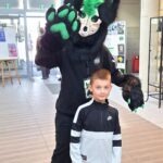 Chłopiec stoi obok maskota w kostiumie potwora podczas ChrzanConu.