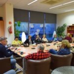 Uczestnicy Dyskusyjnego Klubu Książki siedzą przy długim stole w sali spotkań podczas rozmowy o lekturze.