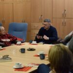 Uczestnicy Dyskusyjnego Klubu Książki siedzą przy stole konferencyjnym podczas spotkania poświęconego powieści "Nieczułość".