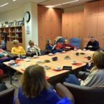Uczestnicy Dyskusyjnego Klubu Książki siedzą przy długim stole w sali konferencyjnej podczas spotkania poświęconego powieści "Nieczułość".
