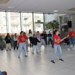 Uczestnicy warsztatów w jasnym pomieszczeniu tańczą i bawią się podczas Dnia Kolorowej Skarpetki.