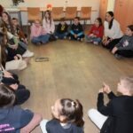 Dzieci siedzą w kręgu na podłodze podczas warsztatów edukacyjnych poświęconych akceptacji różnorodności.