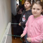 Dwie dziewczynki trzymają sznurówki, uczestnicząc w zajęciach bibliotecznych.