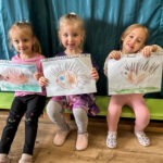 Trzech przedszkolaków prezentuje rysunki jeży wykonane podczas konkursu plastycznego w bibliotece.