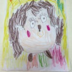 Dziecięca praca przedstawia jeża z brązowymi kolcami, różowymi policzkami i żółtym kółeczkiem na głowie.