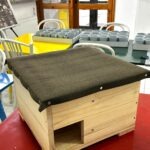 Drewniany domek z ciemnym daszkiem i otworem wejściowym został przygotowany dla jeża.