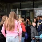 Grupa dzieci z koszyczkami wychodzi z budynku biblioteki.