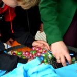 Dziecko trzyma garść kolorowych jajek czekoladowych.