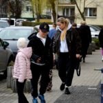 Uczestnicy polowania na jajka pomagają starszej kobiecie przejść przez ulicę.