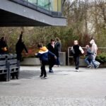 Dzieci z rodzicami uczestniczą w polowaniu na jajka na terenie biblioteki.