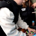 Chłopiec wkłada kolorowe jajka do koszyczka.