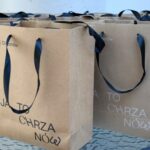 Kilka papierowych torebek z niebieskimi uchwytami i napisem "Chrza Nowa".