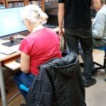 Kobieta siedzi przed komputerem podczas warsztatów z obsługi komputera dla seniorów.