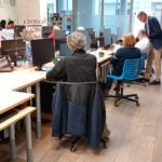 Uczestnicy warsztatów pracują przy komputerach w sali bibliotecznej.