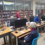 Uczestnicy warsztatów tworzą dokumenty aplikacyjne przy komputerach ustawionych w sali bibliotecznej.