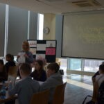 Uczniowie słuchają prezentacji podczas spotkania w bibliotece szkolnej.