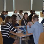 Uczniowie siedzą przy stole w bibliotece podczas zajęć poświęconych językowi polskiemu.