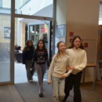 Czwórka dziewcząt przechodzi przez drzwi do biblioteki szkolnej.