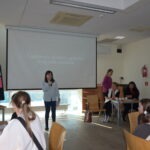 Uczeń prezentuje wystąpienie przed ekranem projekcyjnym w sali bibliotecznej.