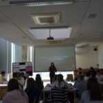 Uczniowie słuchają wystąpienia podczas spotkania zorganizowanego w bibliotece szkolnej.