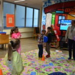 Dzieci bawią się na kolorowej macie podczas zajęć w sali zabaw.