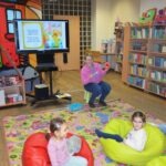 Dzieci słuchają opowiadania wyświetlanego na ekranie podczas zajęć edukacyjnych.
