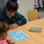 Kobieta pomaga dziecku podczas zabawy edukacyjnej związanej z higieną jamy ustnej.