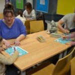 Dzieci pod opieką dorosłych wypełniają kolorowanki podczas warsztatów edukacyjnych na temat higieny jamy ustnej.