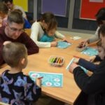 Dzieci siedzą przy stole, korzystając z materiałów edukacyjnych podczas warsztatów dotyczących higieny jamy ustnej.