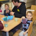 Dzieci uczestniczą w zajęciach, trzymając kubeczki podczas warsztatów edukacyjnych o zdrowiu jamy ustnej.