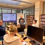 W sali szkoleniowej prowadzone są warsztaty dotyczące e-usług publicznych, a na ekranie wyświetlana jest prezentacja.