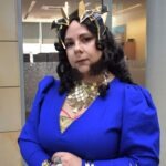 Kobieta przebrana za Galadriel, władczynię elfów, pozuje w stroju z długą złotą biżuterią i koroną.