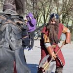 Dwóch mężczyzn przebranych za bohaterów fantasy uczestniczy w konwencie, prezentując kostiumy inspirowane "Władcą Pierścieni".