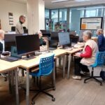 Uczestnicy warsztatów korzystają z komputerów w bibliotece podczas spotkania dla osób poszukujących pracy.